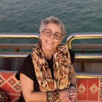 Woman in a black shirt with glasses and a colorful scarf around her neck.
